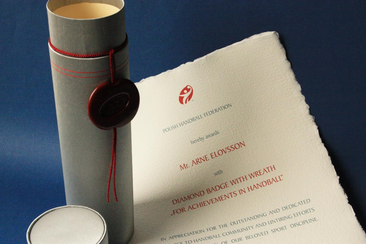 Nr 04.32 • Odznaka Diamentowa Związku Piłki Ręcznej w Polsce. Papier czerpany. Tuba introligatorska srebrna. Pieczęć lakowa. Karneol Nr 04.32 • Odznaka Diamentowa Związku Piłki Ręcznej w Polsce. Papier czerpany. Tuba introligatorska srebrna. Pieczęć lakowa.